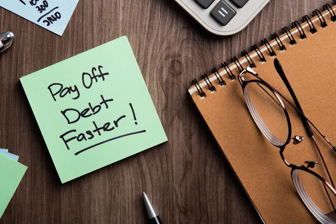 Pay off debt faster handwritten on memo and calculator.