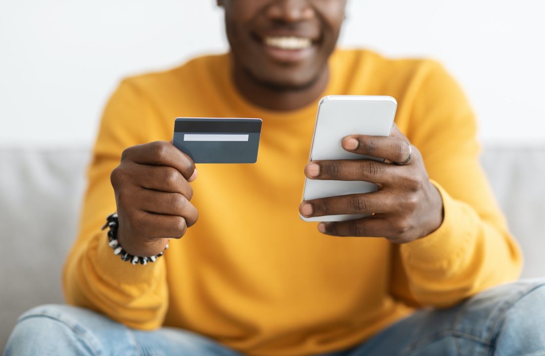 Unrecognizable black guy holding cellphone and credit card