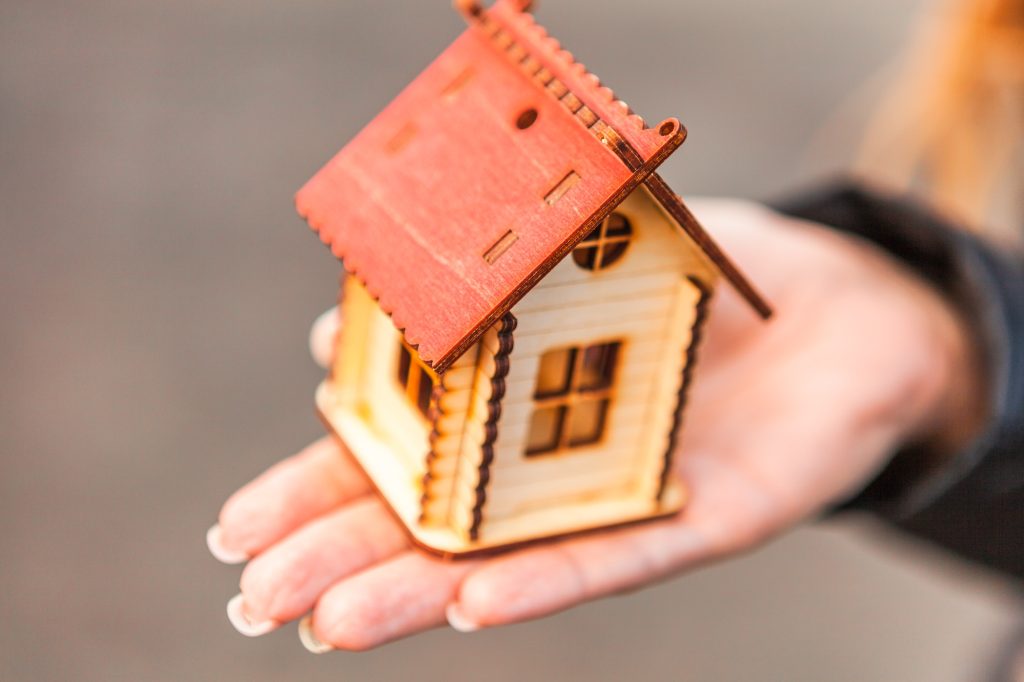 Model of a house in the girl’s hand, the concept of buying a home on credit or a mortgage.