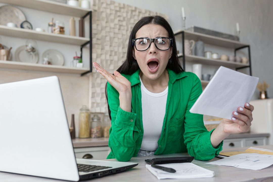 Home finances, housewife shocked looking at camera and screaming frustrated