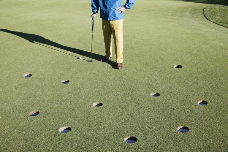 A golfer with way too many choices in possible putts on the greeen of a golf course.