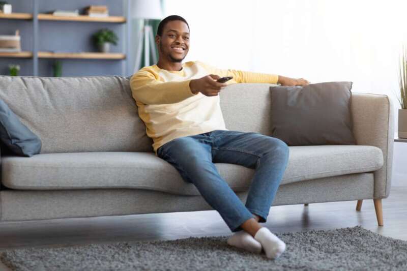 Relaxed african american guy switching channels on TV